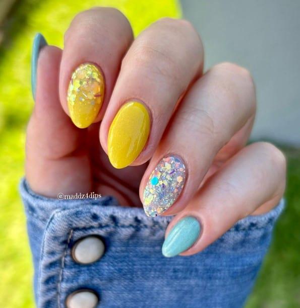a woman with blue and yellow nails with added glitters for accent