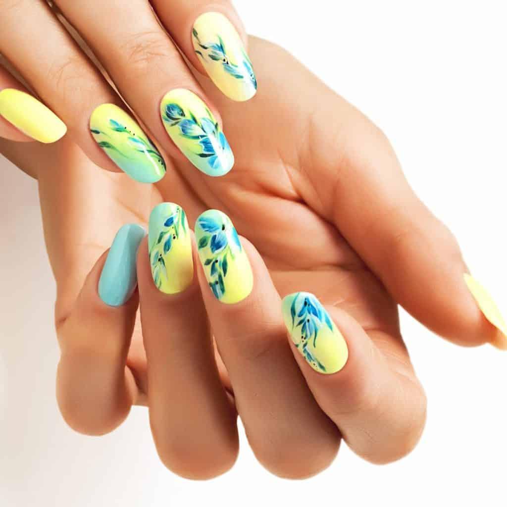 a woman's long nails with yellow base color and delicate flowers in blue