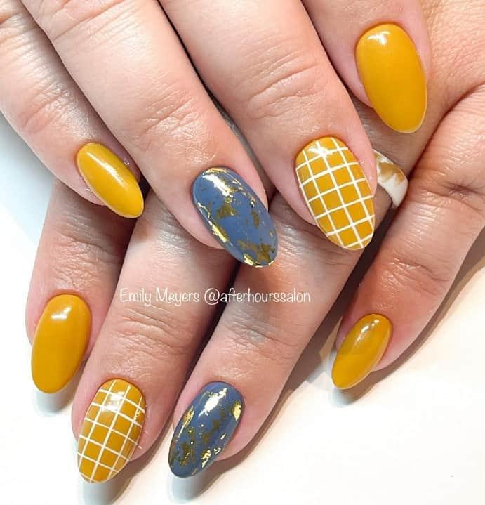 a woman's nails colored in yellow and blue with white grids and gold as accent