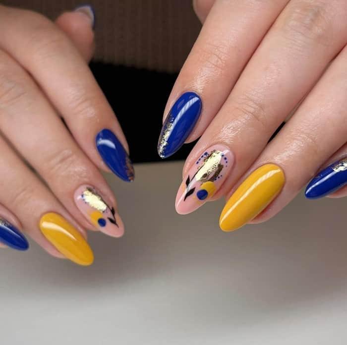 a woman's oval nails painted in blue and yellow with abstract accent design
