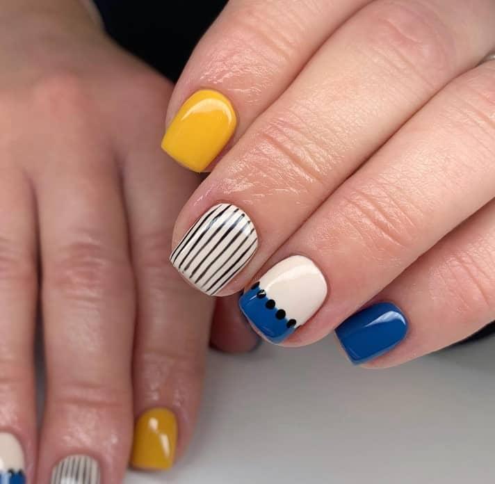 royal blue and yellow nail designs on short nails with black lines and dots as accent