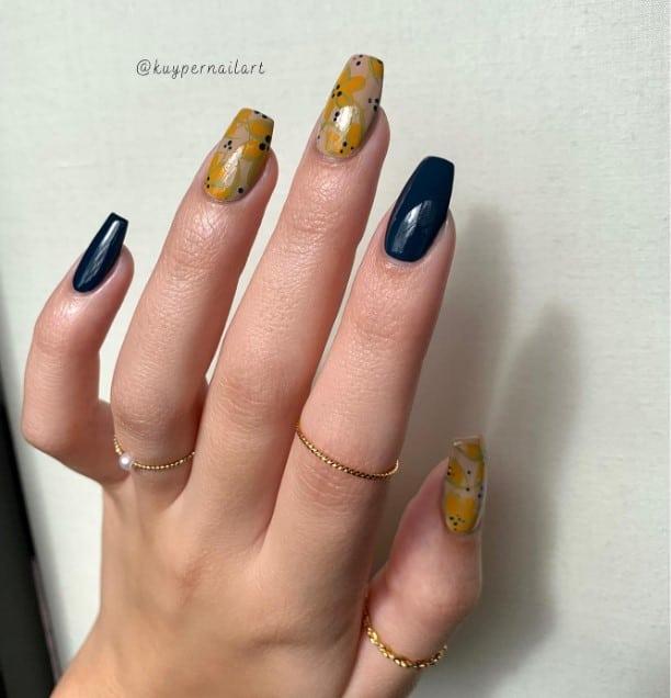 a woman with ballerina nail shaped and floral accents in yellow to the nude accent nails