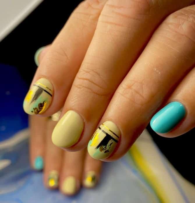 a woman with pale blue and yellow colored nails with abstract accent