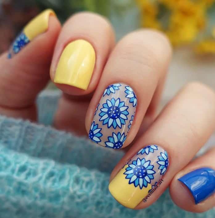 Bright yellow and beautiful blue nails look extra delightful with intricate blue flowers