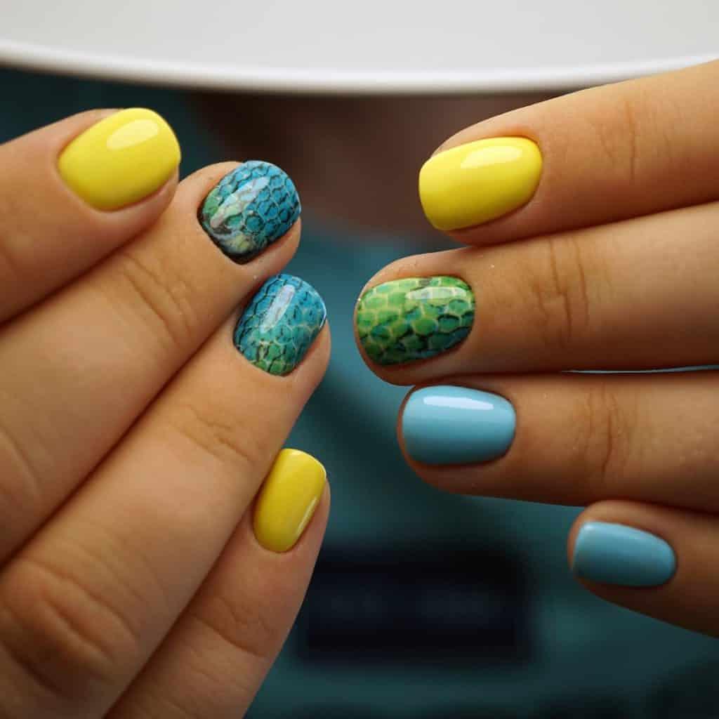 stunning blue and yellow nails add turquoise and sea green colors to the mix along with fish scale-inspired nail art