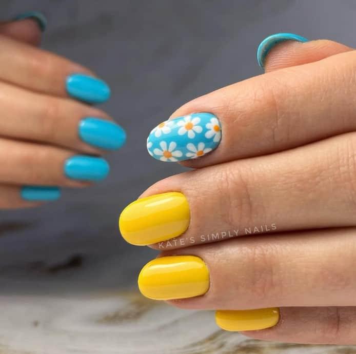 a yellow and blue summer nails with daisy in one nail