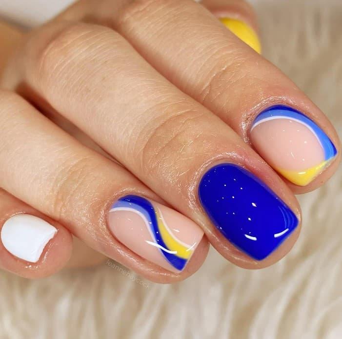fun glossy blue and yellow nails with blue swirls as accent