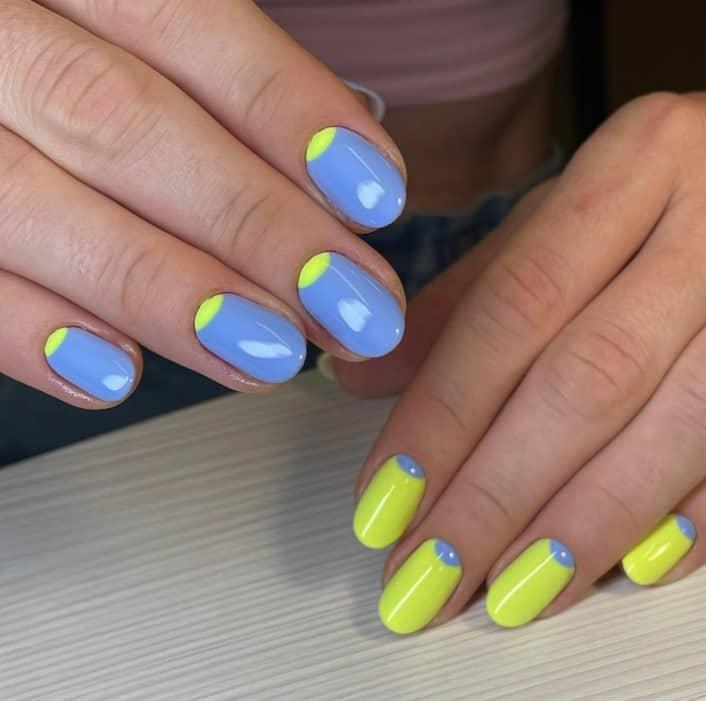 a woman with fun blue-and-yellow nail design features light blue nails on one hand and yellow nails on the other hand