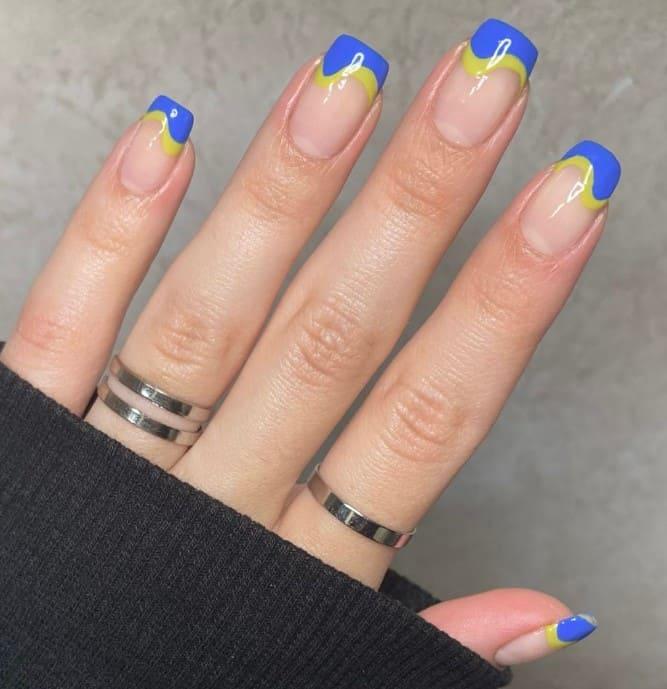 a woman with blue and yellow wavy French nail tips