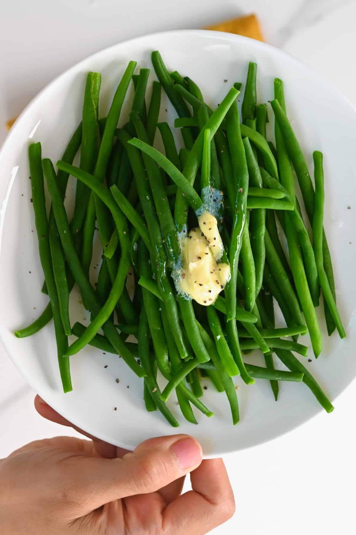 Boiled green beans topped with butter, salt, and pepper