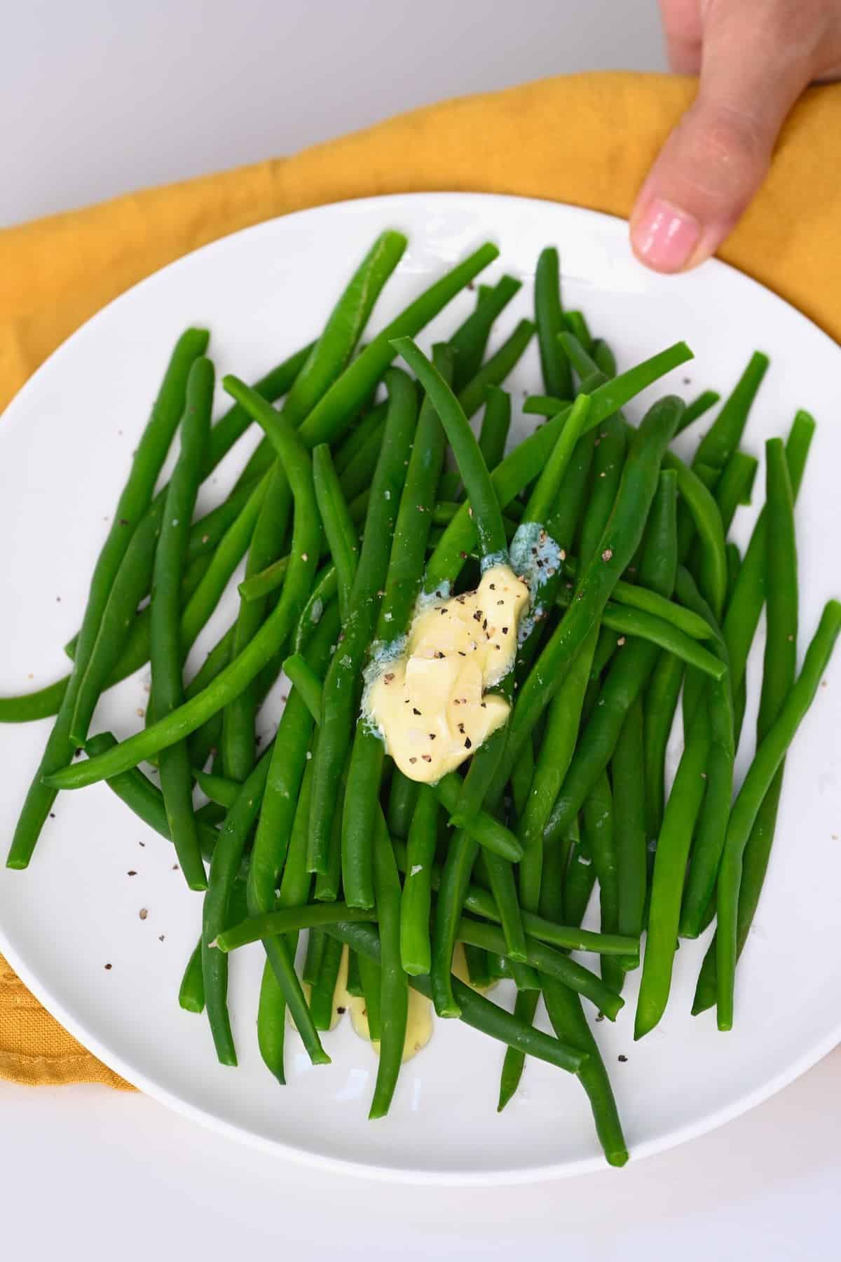 Boiled green beans topped with butter, salt, and pepper