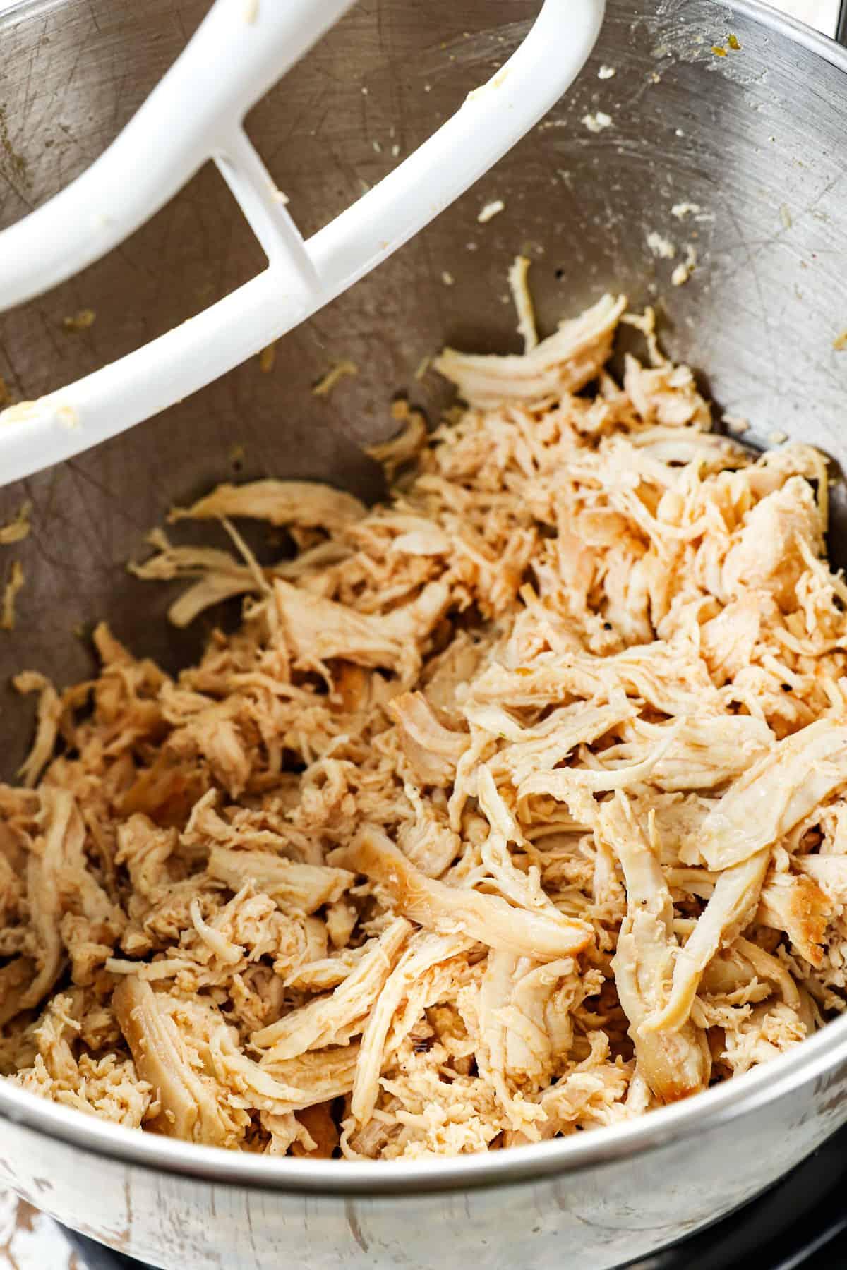 showing how to make shredded chicken by shredding it with the paddle attachment on a stand mixer