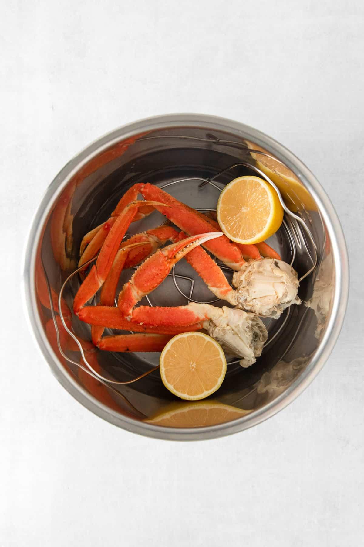Snow crab legs and lemon in the bowl of an Instant Pot.
