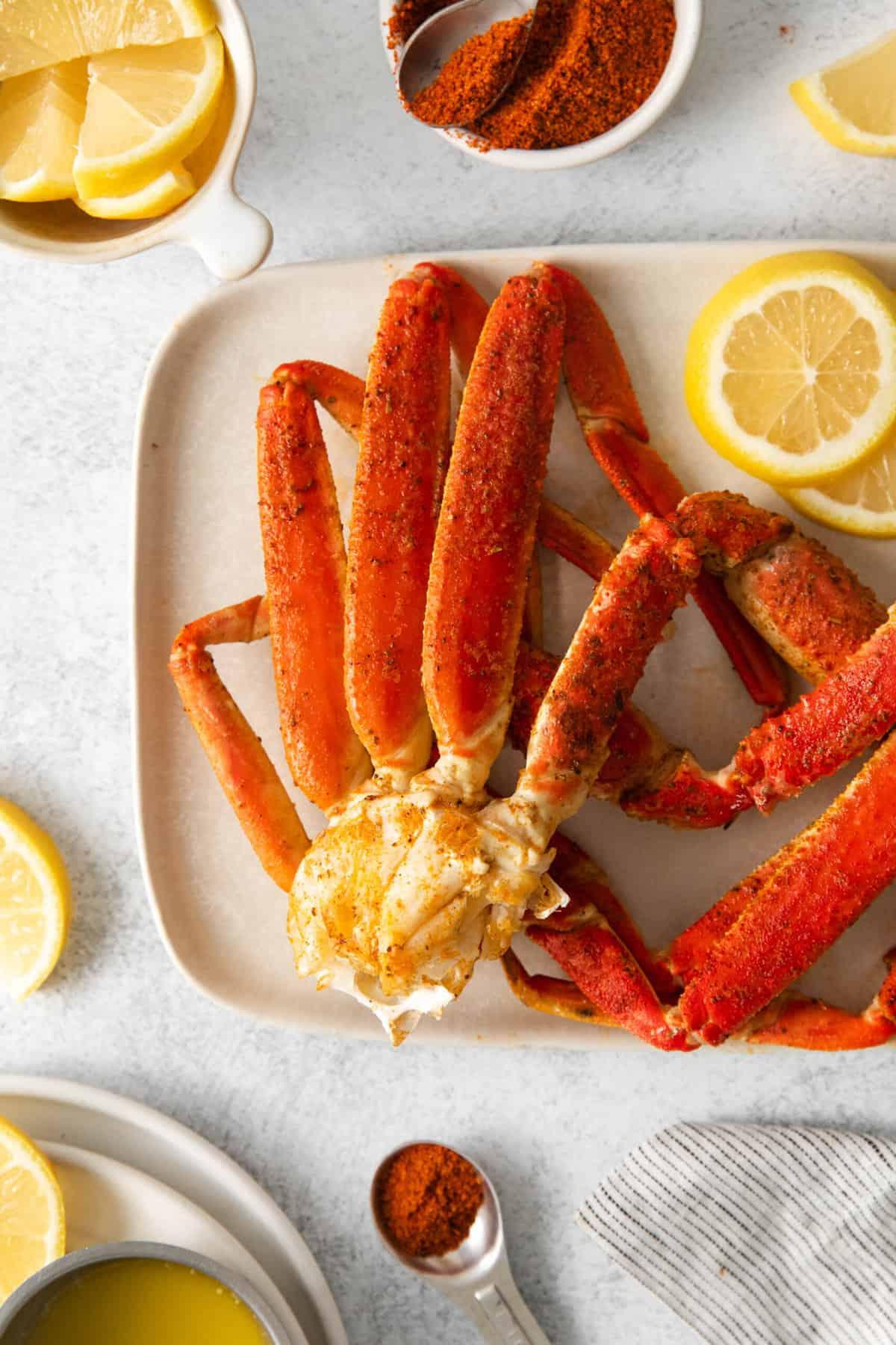 Cooked snow crab legs on a white plate with lemon.