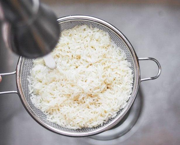 Rinsing white rice in a sink