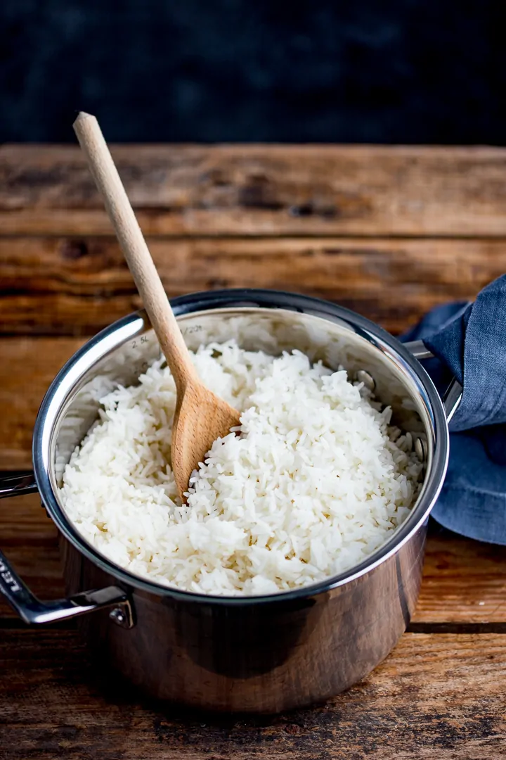 Boiled rice in a pan with a wooden spoon in a pan