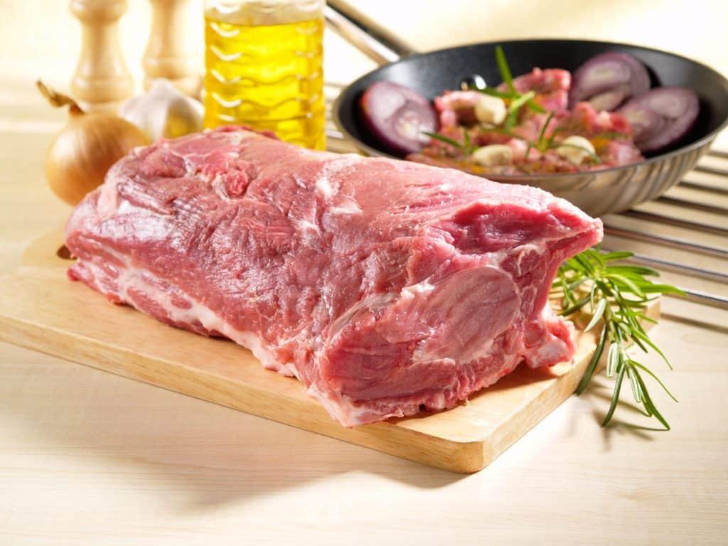 raw pork shoulder square cut on kitchen cutting board