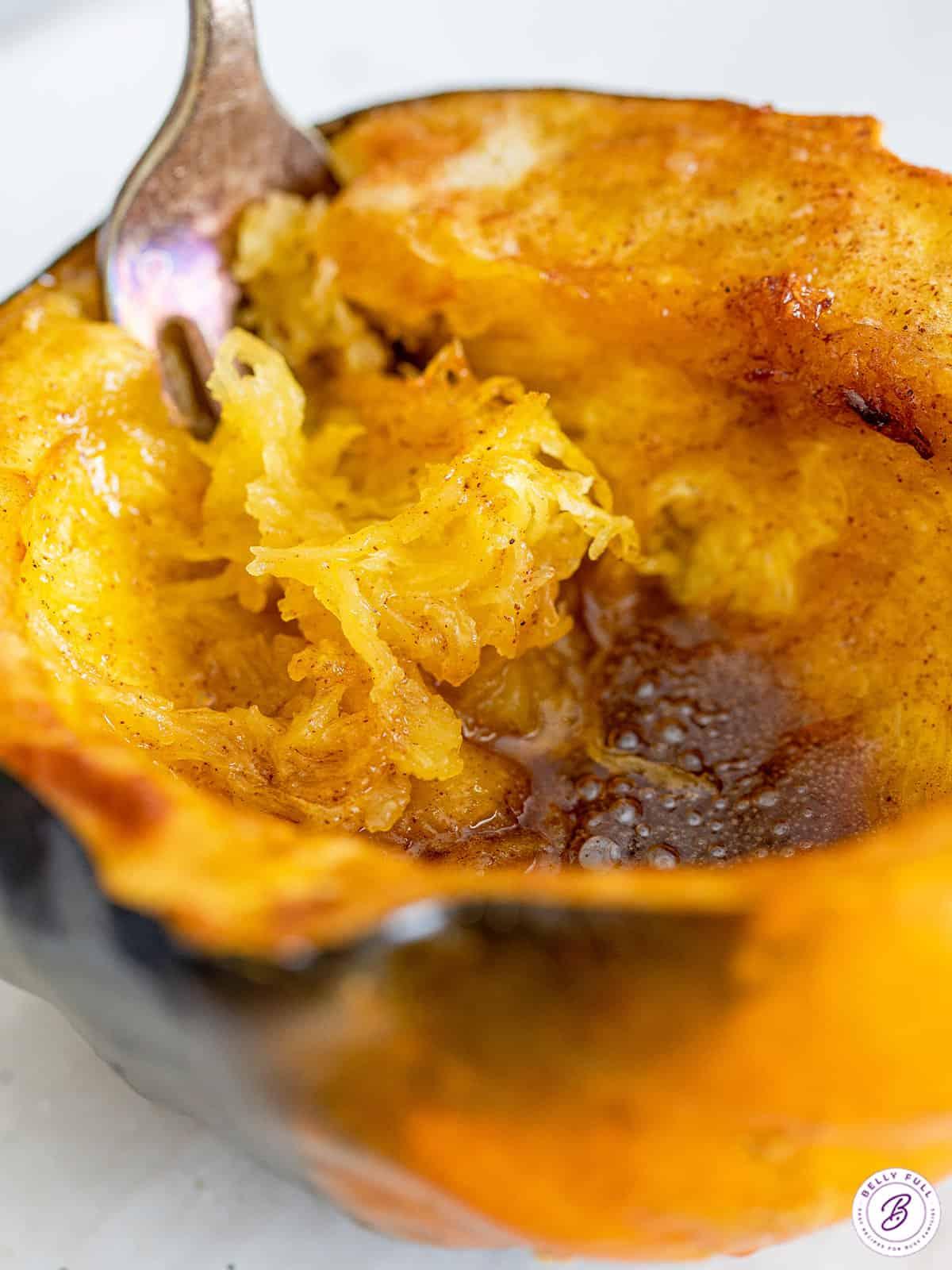 A fork scooping out the inside of an air fryer acorn squash