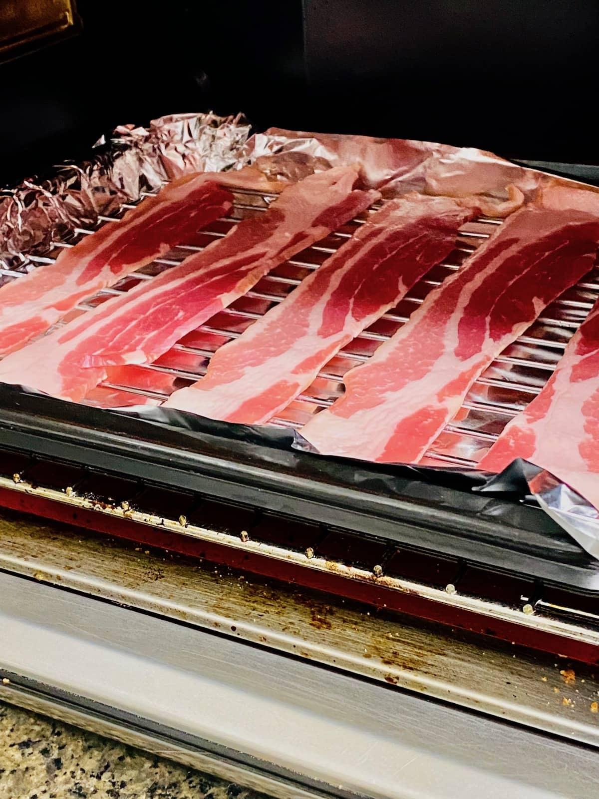 Packet of bacon in front of a toaster oven set to 425 degrees.