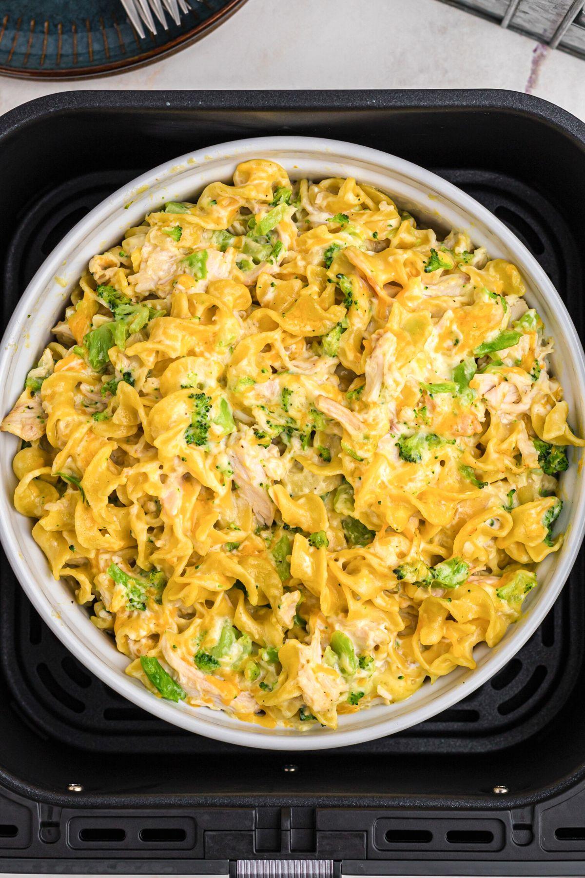 Golden cheesy pasta and chicken mixed in a casserole dish in the air fryer basket