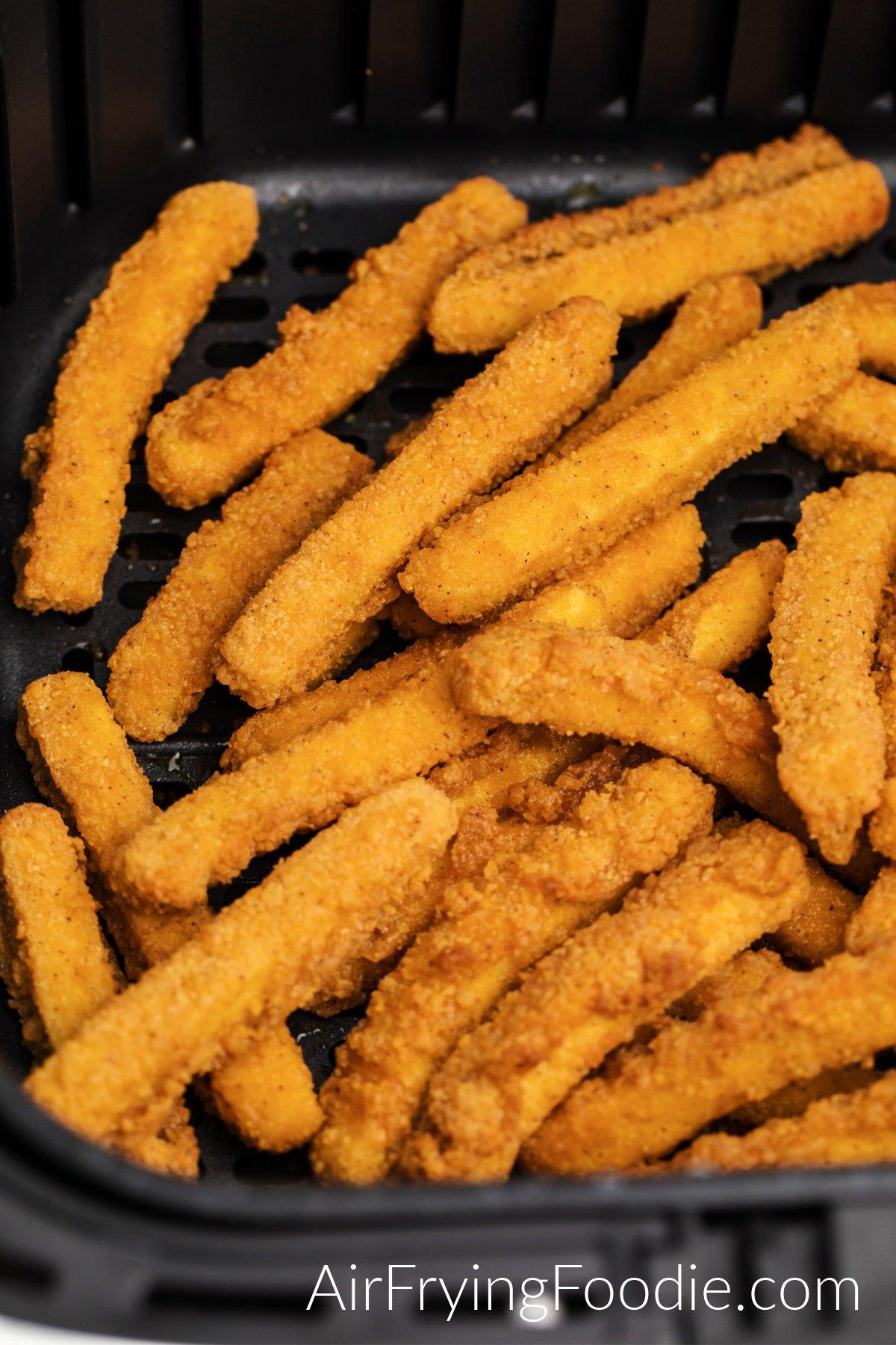 Fully cooked chicken fries in air fryer basket.