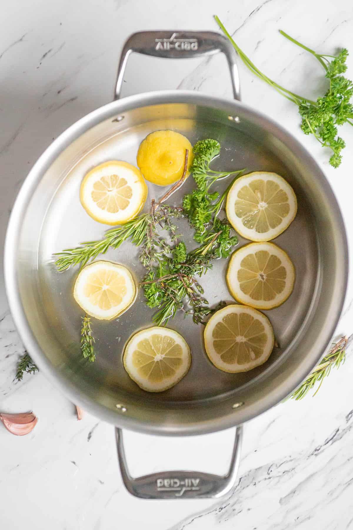 adding lemon and herbs to water to steam crab legs.