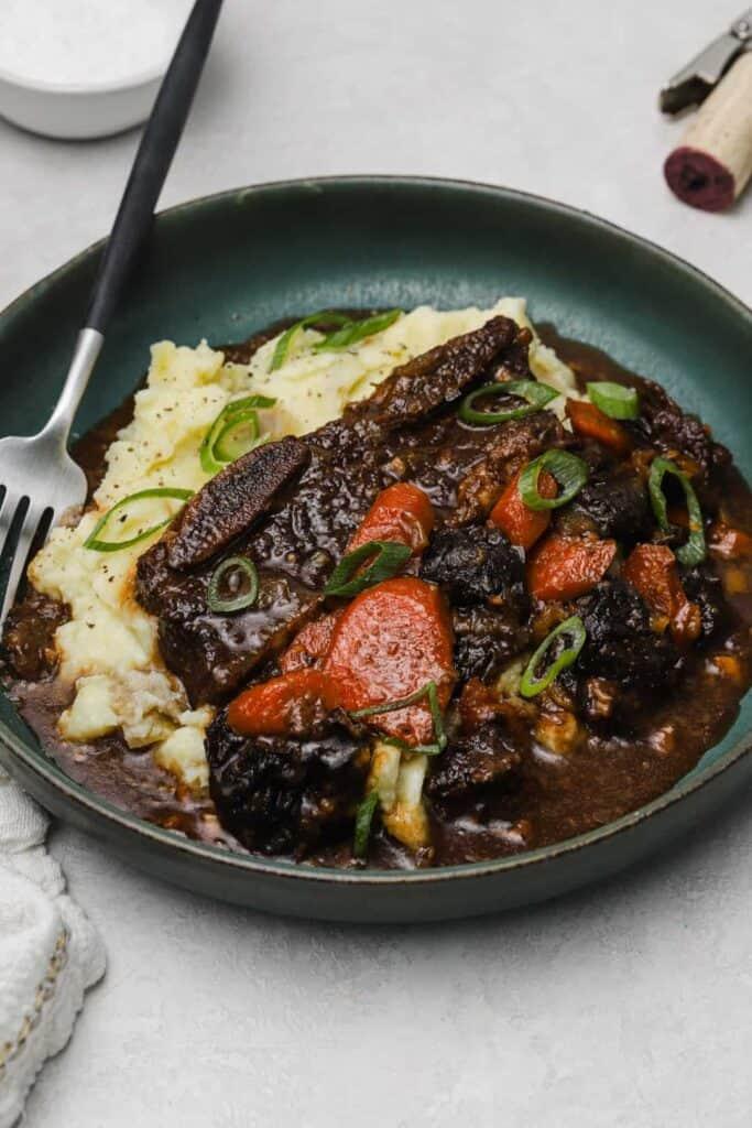 Flanken ribs with prunes and carrots on a plate with mashed potatoes