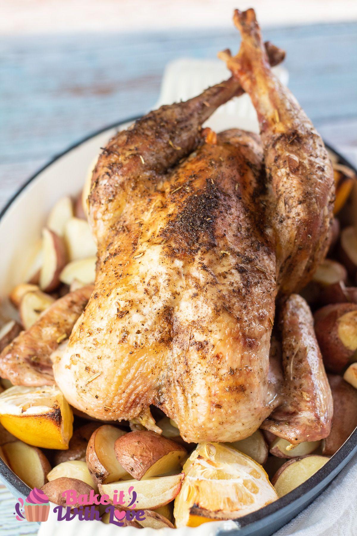 Roasted pheasant in a roasting pan with potatoes and lemons