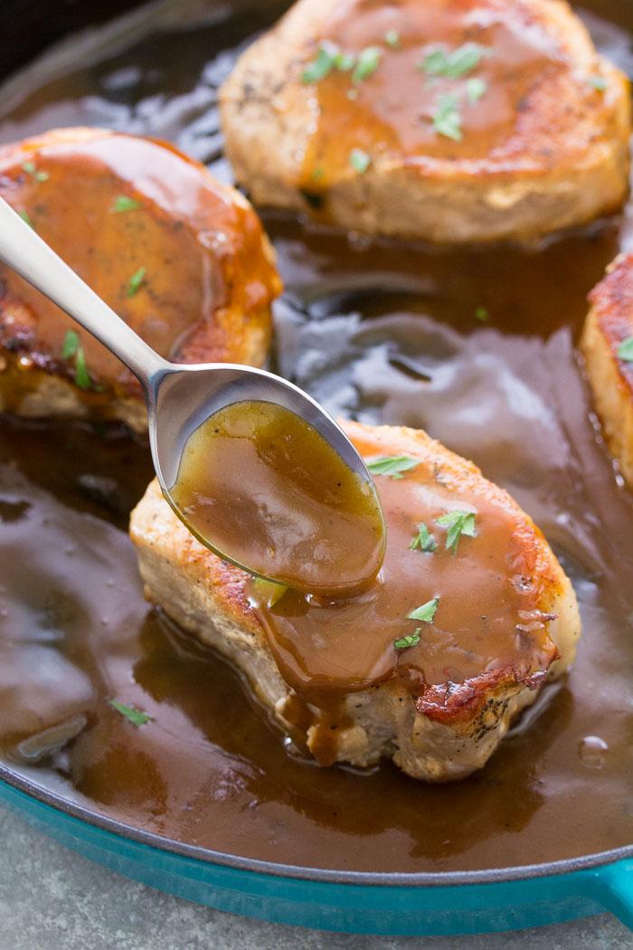 Spooning honey mustard sauce over pan-seared pork chops.