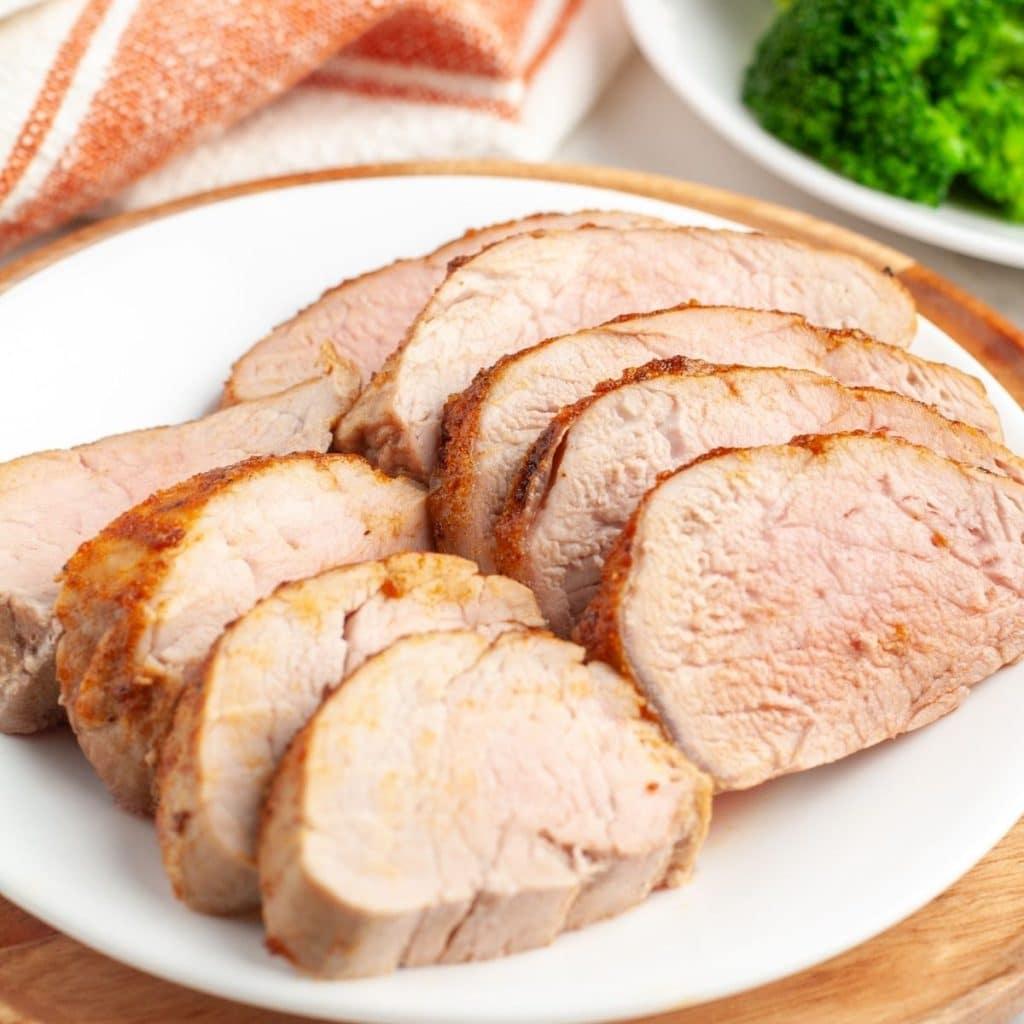 Pork loin with bowl of spices and oil.