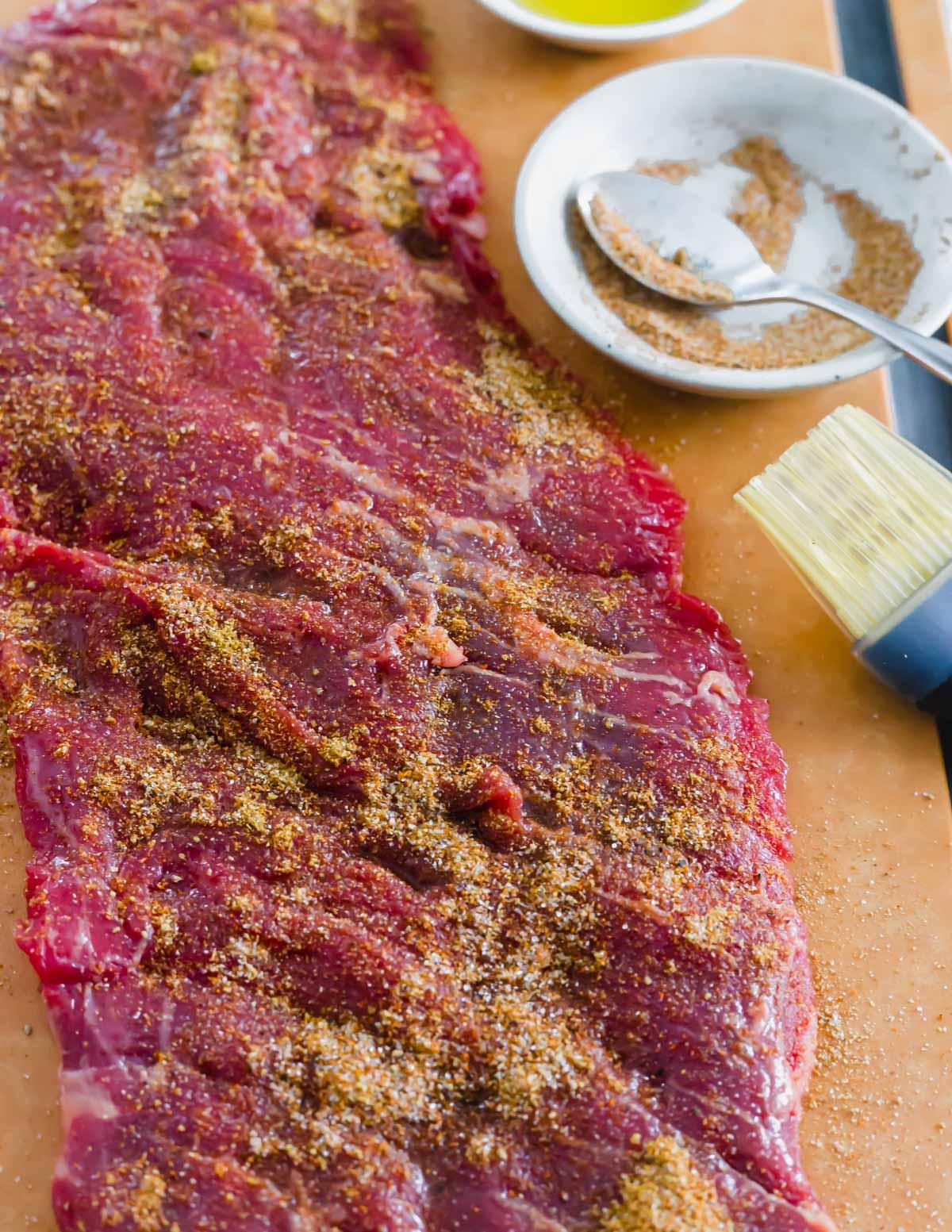 Seasoning mix rubbed onto skirt steak on a cutting board.