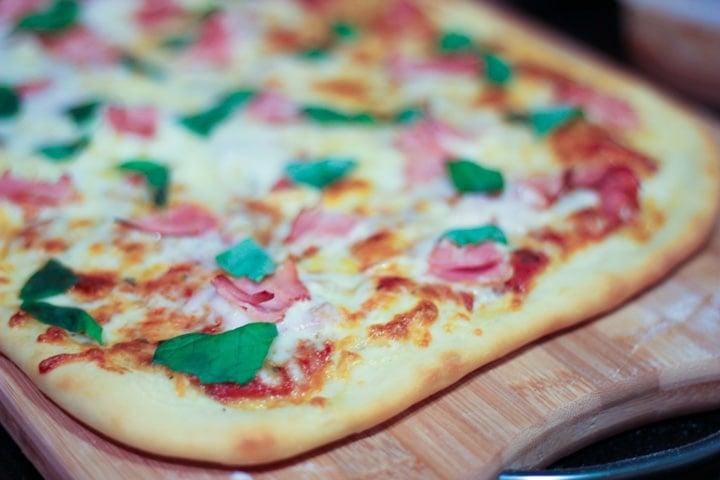 step by step guide to adding pizza toppings to homemade pizza with red pizza sauce cheese and ham