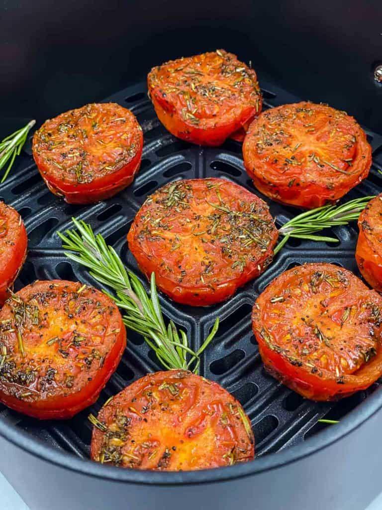 Roasted tomatoes in an air fryer basket and with rosemary.