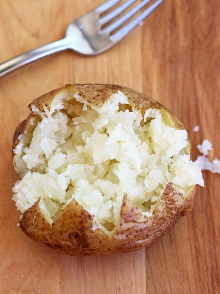 Baked potato opened and fluffed with a fork.