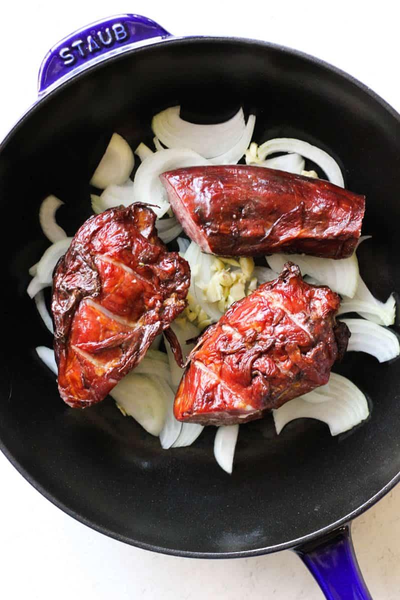 smoked turkey necks with sliced onions in the pan