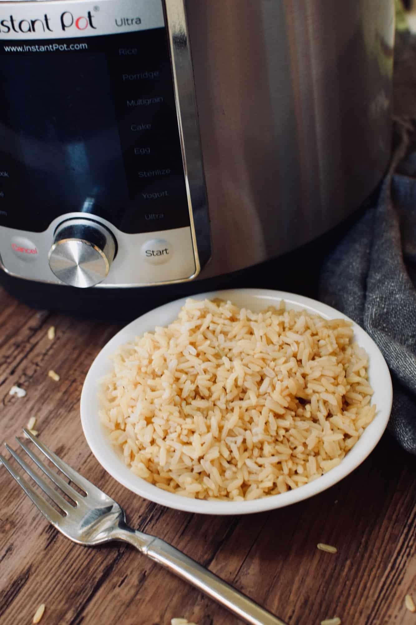 A fork and bowl of brown jasmine rice next to an Instant Pot.