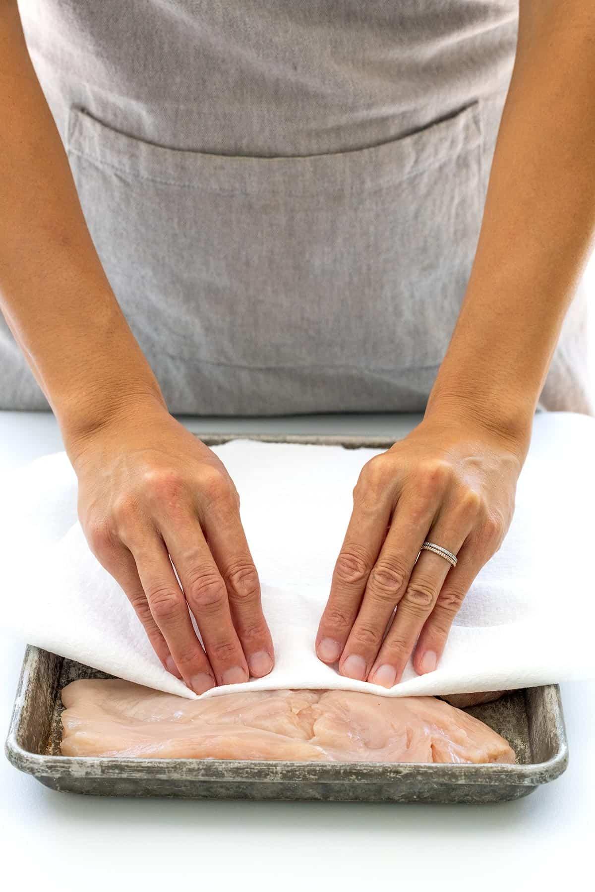 Drying the chicken's surface with paper towels