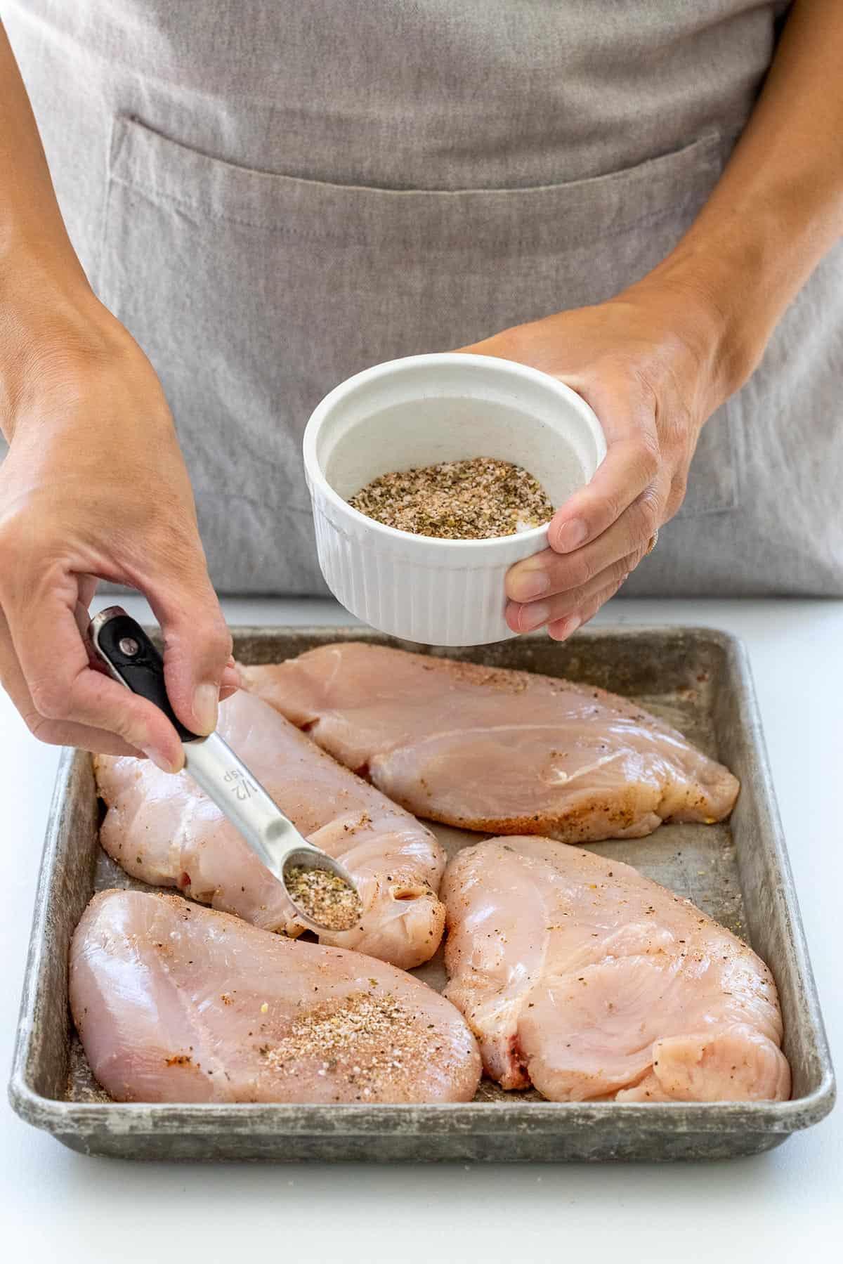 Sprinkling dried seasonings over chicken breasts