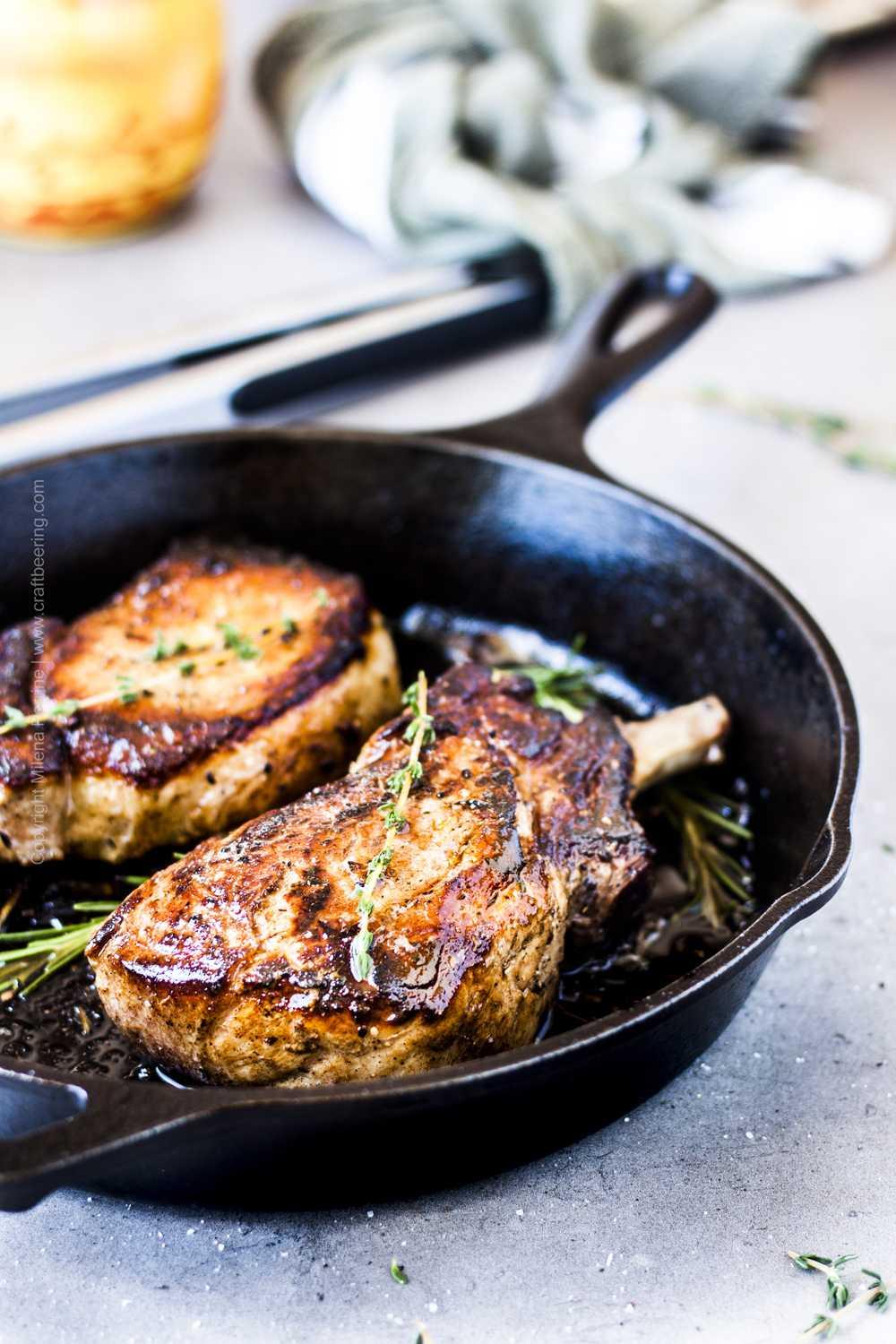Thick cut pork chops in cast iron skillet with fresh herbs