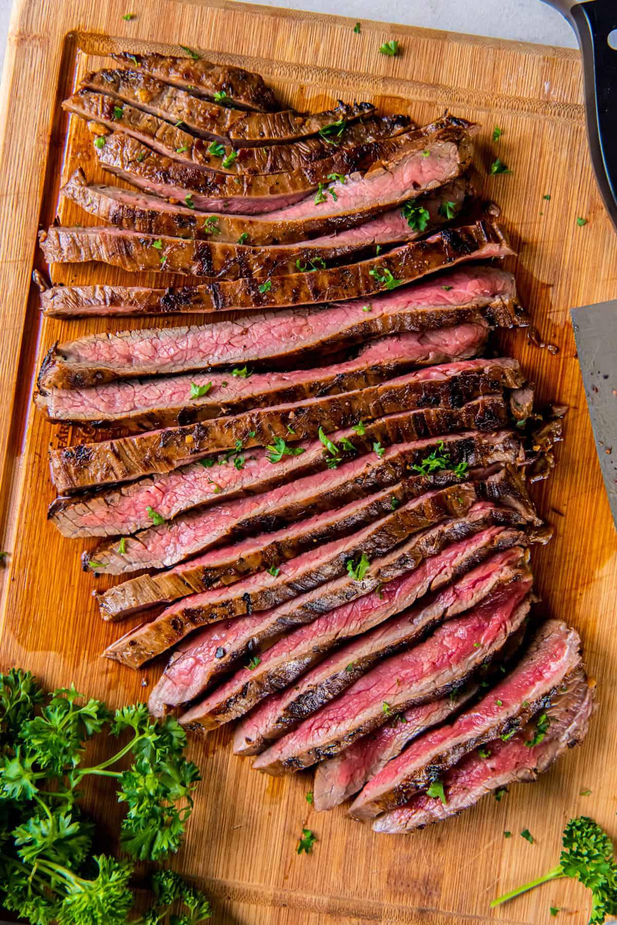 Sliced cast iron flank steak on a cutting board for serving.