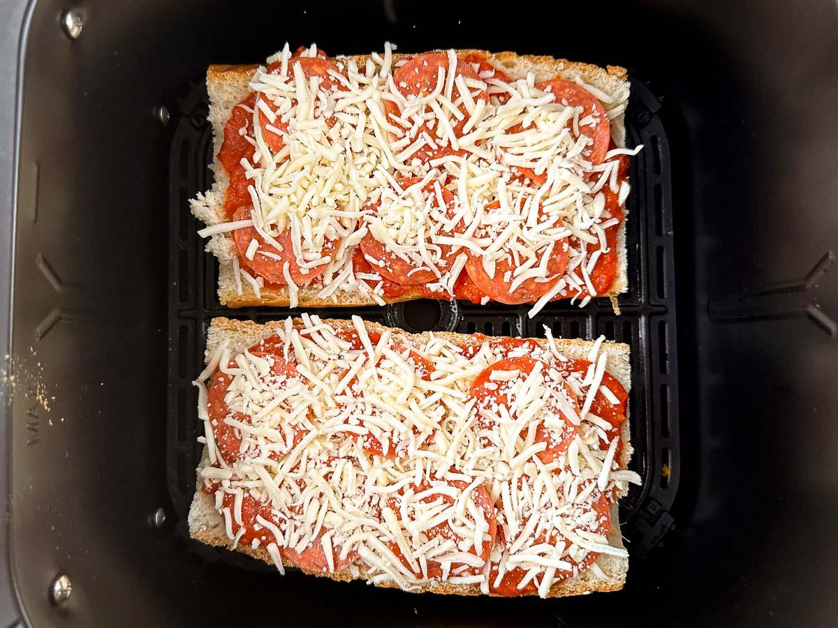 air fryer basket with 2 French bread pizzas ready to bake