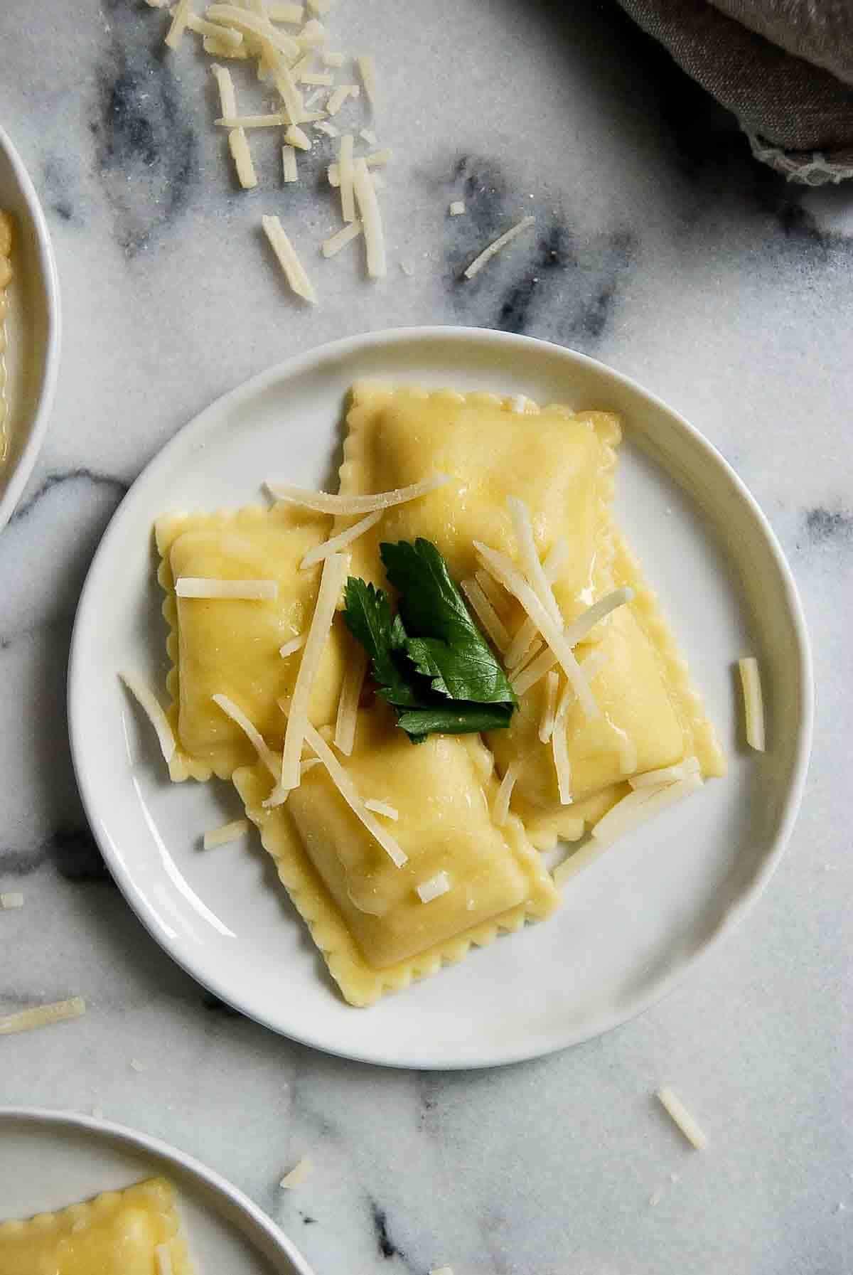plate of cheese ravioli with garlic butter sauce, parmesan cheese and parsley. Cooking Frozen Cheese Ravioli is so easy and there are so many different ways you can use it! Below are my five favorite ways to cook frozen cheese ravioli for an easy meal or appetizer. Intro Frozen cheese ravioli is one of those freezer staples that I think everyone should have. It provides you with a simple way to make an endless variety of meals. Not only does it cook in minutes, but it’s incredibly versatile and can be used in so many ways to create a delicious dinner or appetizer. I’ve used it on its own in a simple pasta sauce, breaded baked to use as an appetizer with some marinara dipping sauce, or even as an easy substitute for noodles and ricotta cheese in a Lazy Lasagna. The options are endless and if you’re a parent, or simply a last-minute kind of cook (I happen to be both), frozen cheese ravioli is something you’ll want to have on hand almost all of the time. (You’ll always find a package of it in my freezer!). Why Use Frozen Ravioli? There are so many reasons this easy pasta has become a staple in our house: Cooks Fast. Sure, you can buy premade fresh ravioli, which probably tastes better, but if it’s speed you’re after, you can