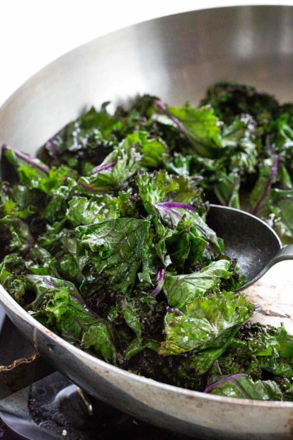 cooking sautéed kale in a metal skillet