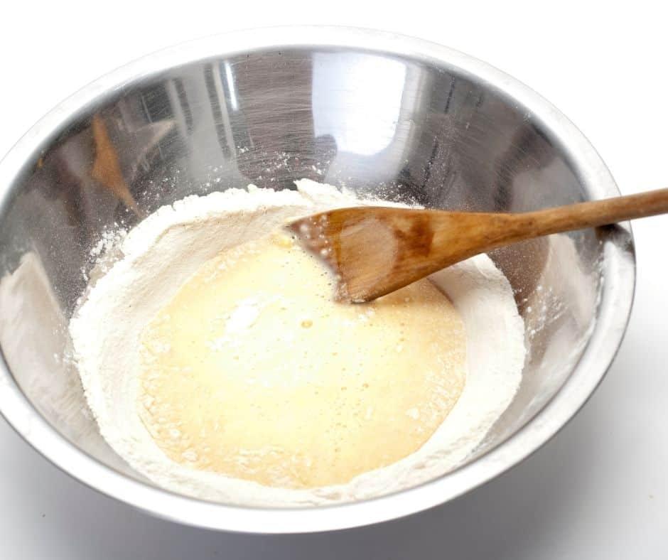 Stirring pancake batter in a silver bowl.