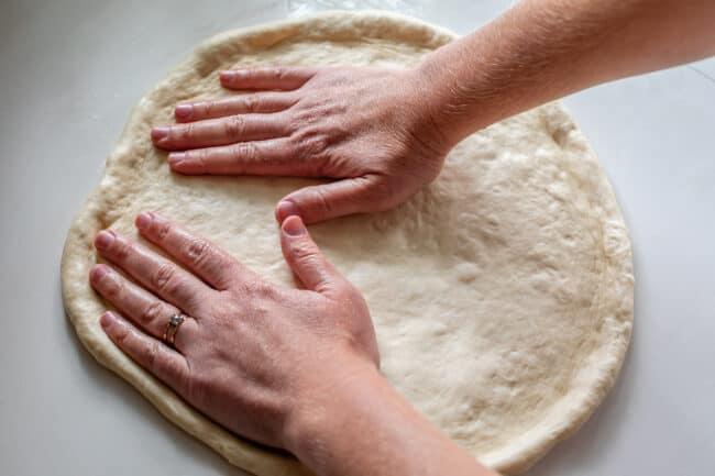spreading pizza sauce on pizza dough