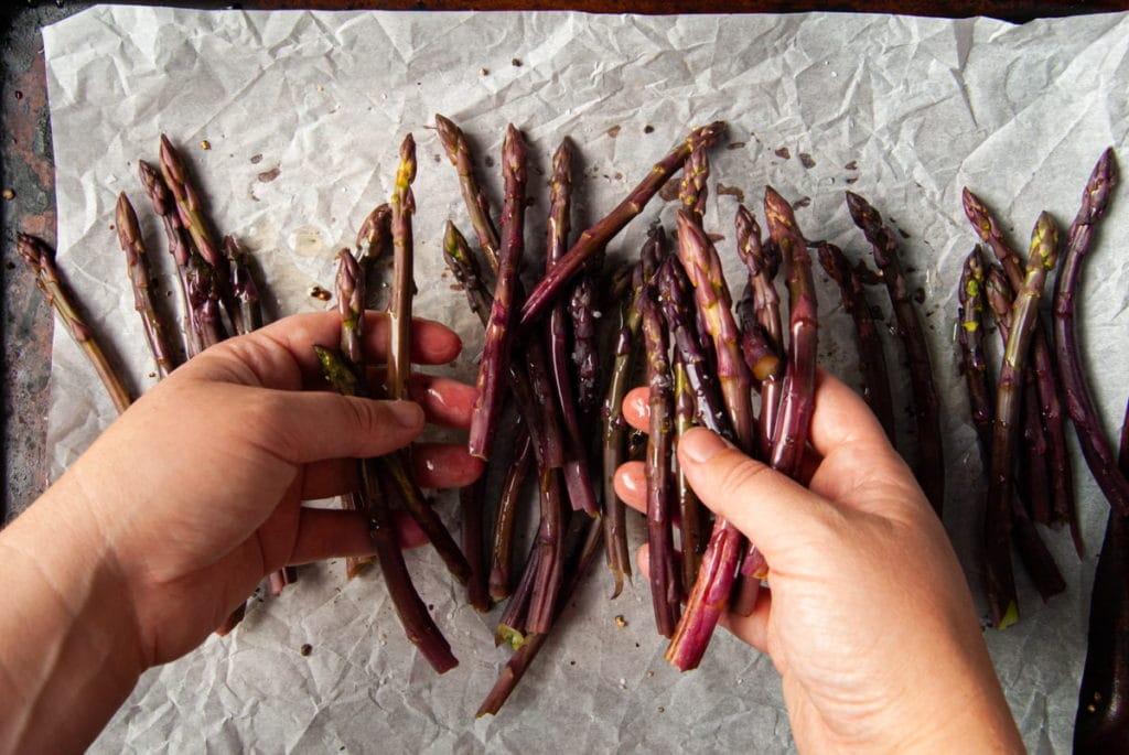 using hands to toss asparagus in olive oil