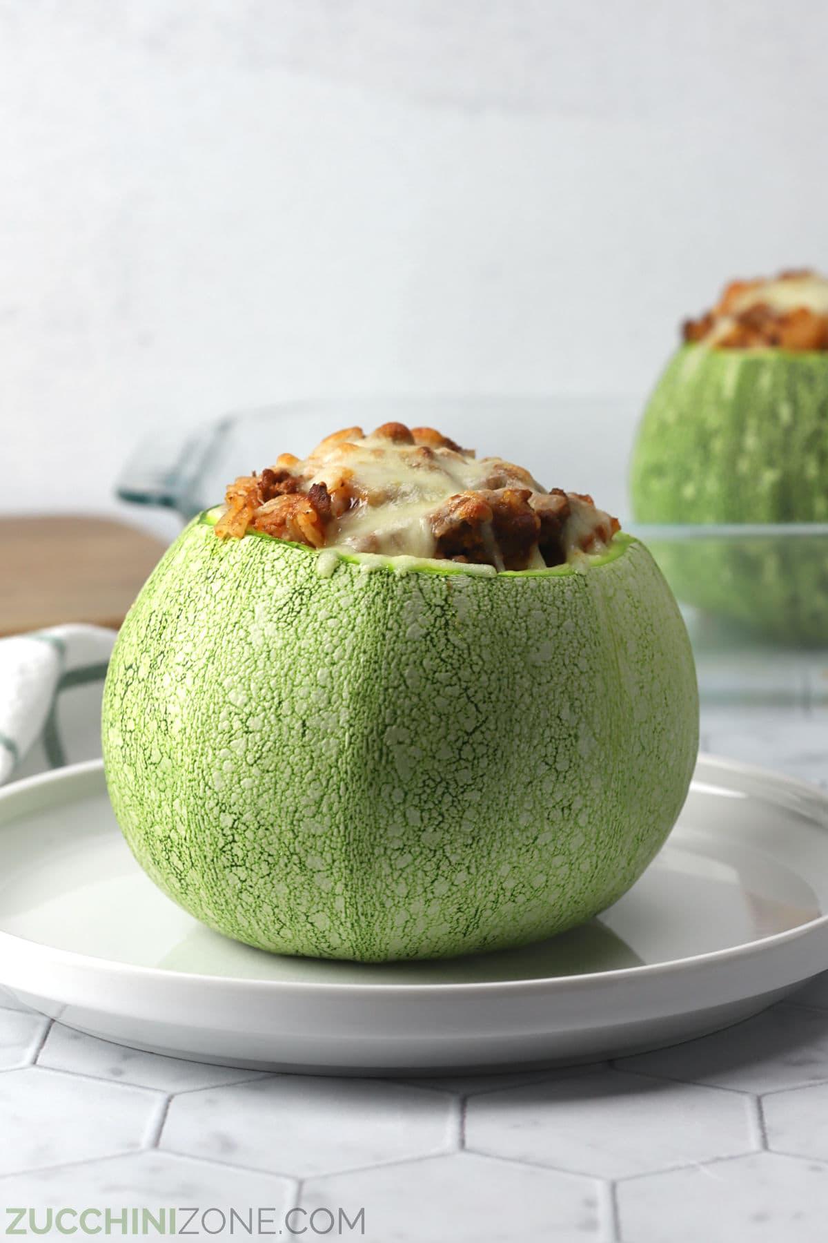 Stuffed round zucchini on a white plate for serving.