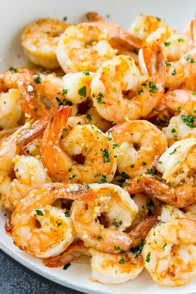 A skillet of shrimp in garlic butter sauce, garnished with parsley.