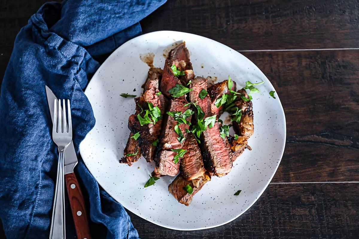 Sliced T bone steak dinner idea on a plate with silverware