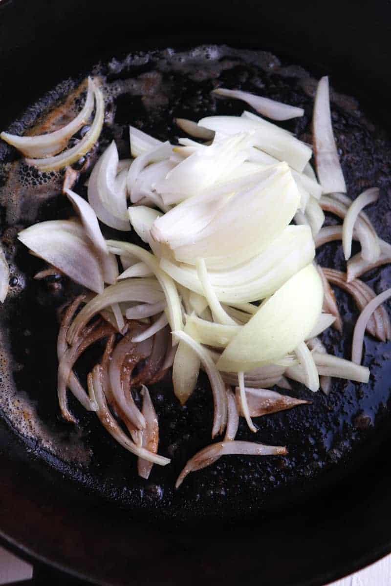 sliced onions in a cast iron skillet